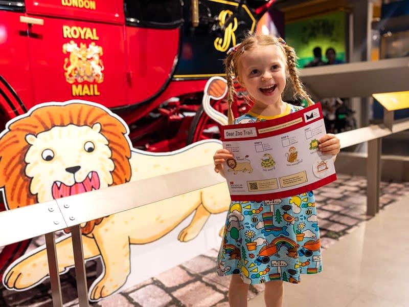 Small white girl holding a Dear Zoo exhibition trail map