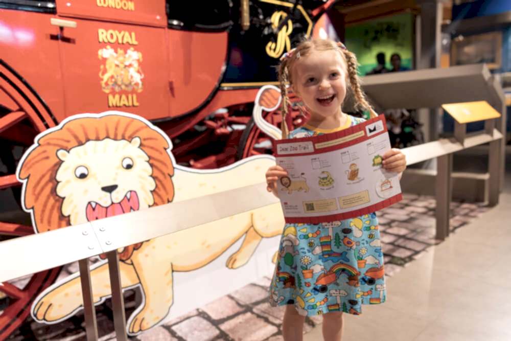 Small white girl holding a Dear Zoo exhibition trail map