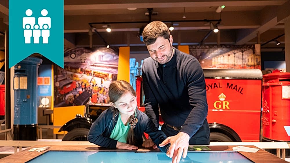 A parent and child exploring the touch table in The Postal Museum exhibition space.