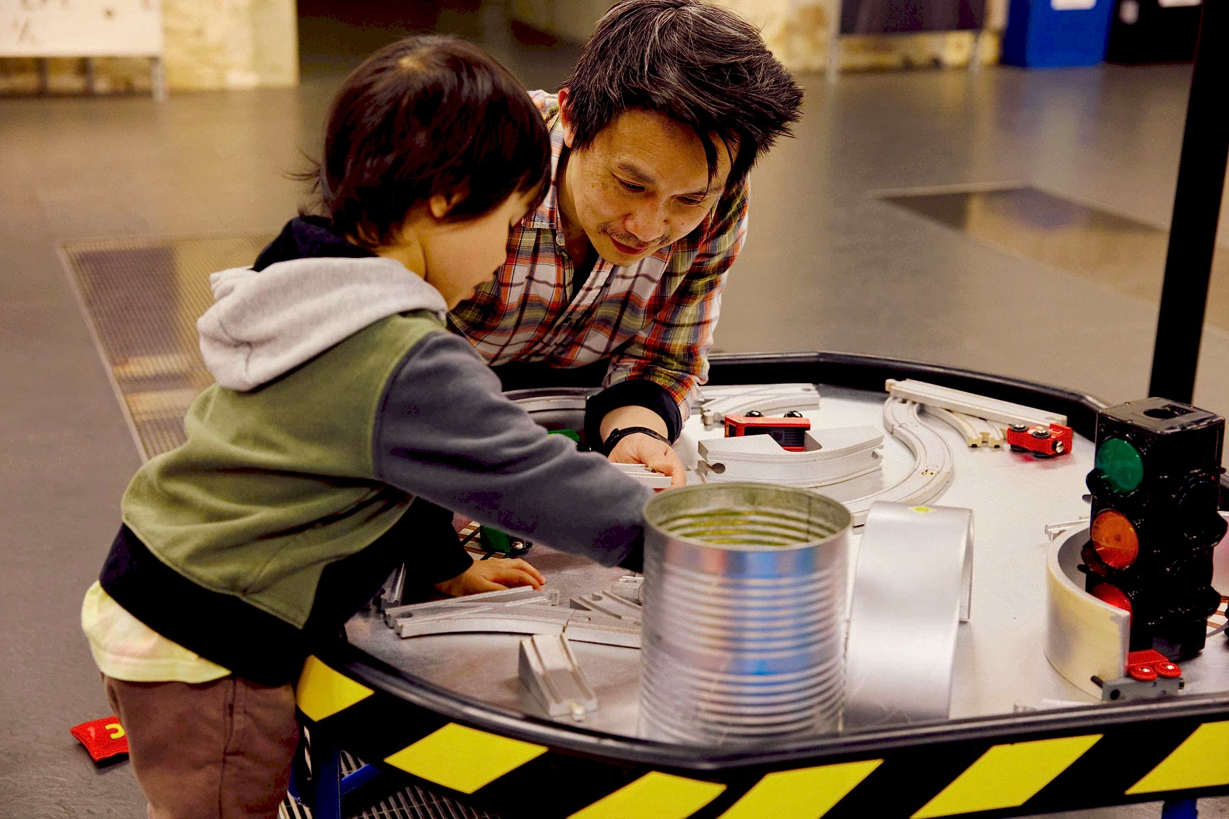 Father and son play with toy trains and train tracks. They look very invested in their play.