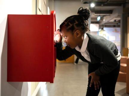 A child looking into a postbox in the exhibition space.