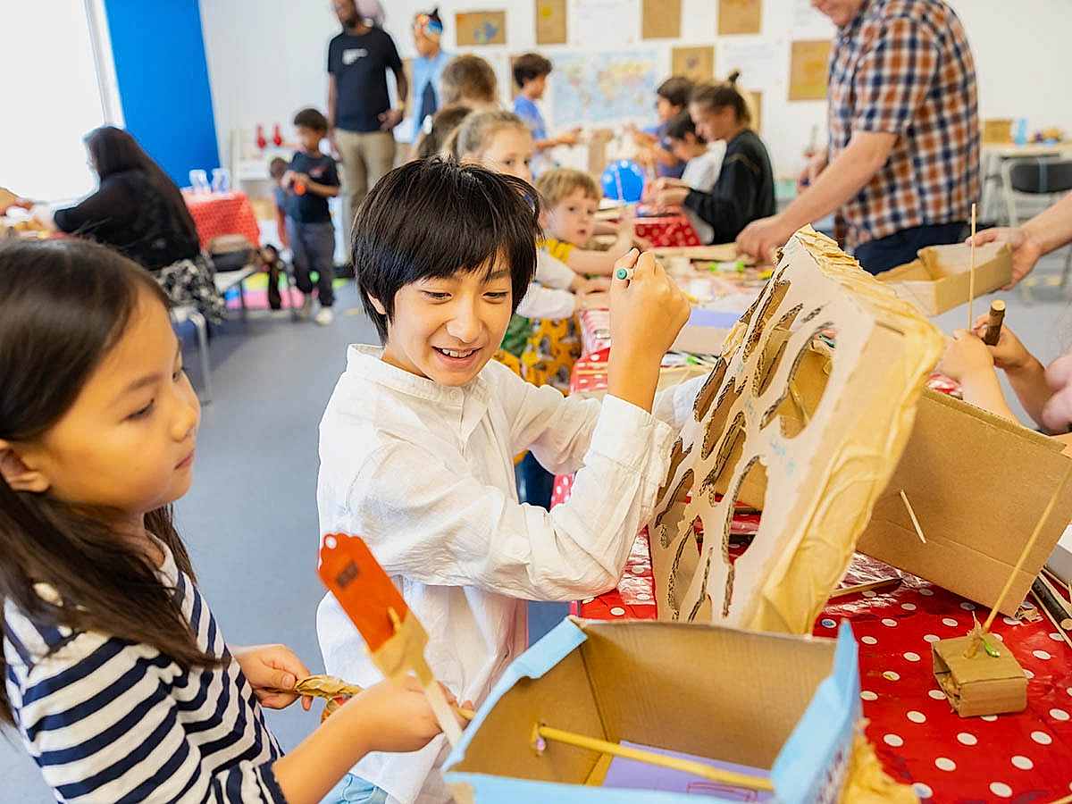 Children at an arts and crafts activity colouring with cardboard and paper.