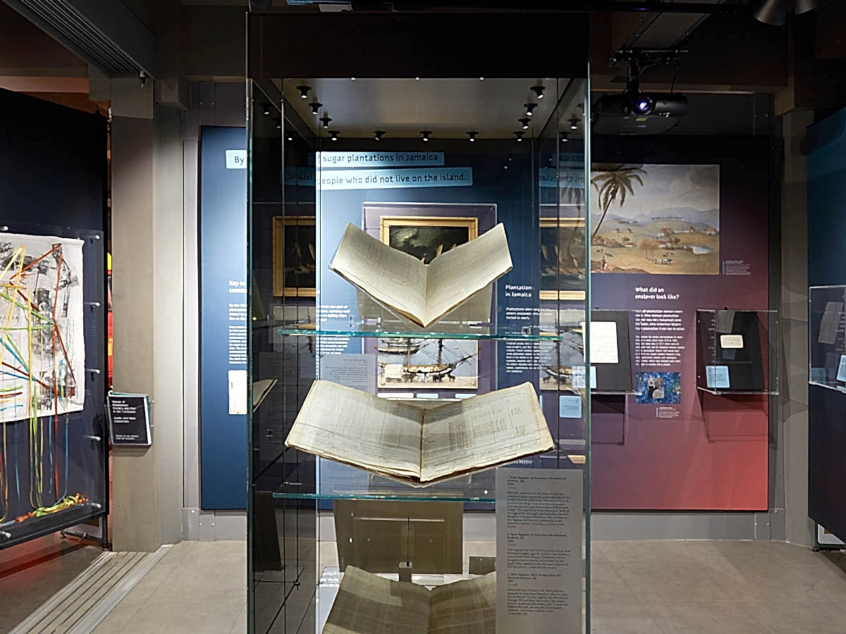 A glass exhibition case containing large books.